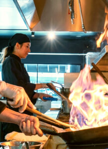 Chef cooking with flames in kitchen at The Baht Medellin